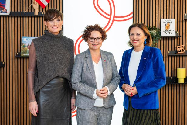 Drei Frauen stehen vor einer Wand mit österreichischem Design.
