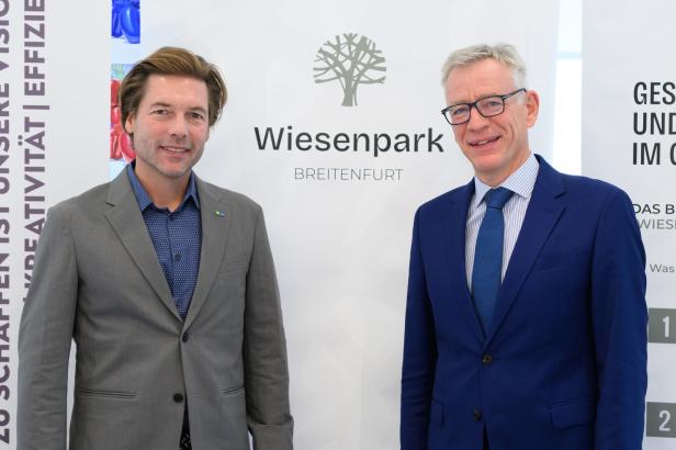 Zwei Männer stehen vor einem Transparent