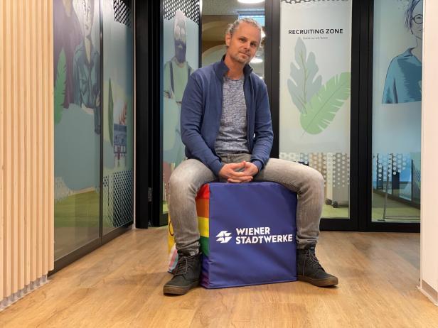 Der Seitenwechsler Michel Fleck sitzt auf einem Würfel mit Firmenlogo