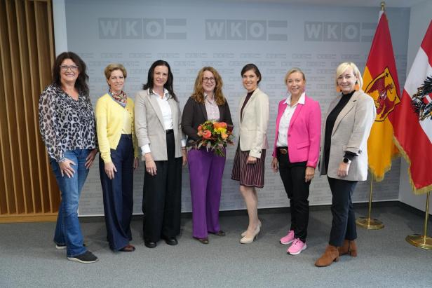 Eine Gruppe von sieben Frauen steht vor einem Hintergrund mit dem WKO-Logo und österreichischen Flaggen.