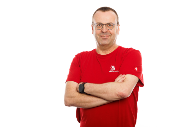 Ein weißer Mann in einem roten T-Shirt vor einer weißen Wand