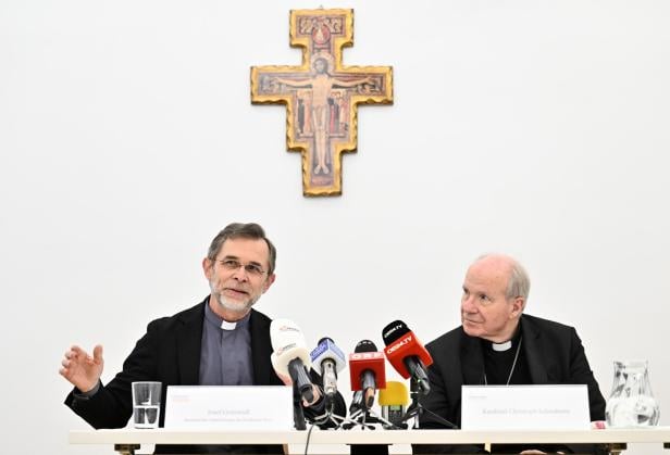 PK ERZDIÖZESE WIEN ANL. DES RÜCKTRITTS VON KARDINAL SCHÖNBORN: SCHÖNBORN, GRÜNWIDL Kardinal Christoph Schönborn und Josef Grünwidl sitzen vor Mikrofonen unter einem Kreuz.