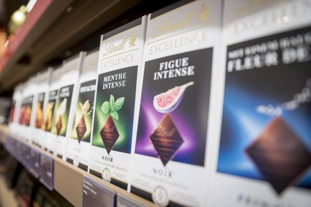 Reihe von Lindt Excellence Schokoladentafeln im Regal, darunter Sorten wie Menthe Intense und Figue Intense.