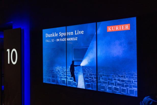 Ein Bildschirm zeigt "Dunkle Spuren Live" mit einer Person, die einen Lichtstrahl auf eine Menge alter Fernseher richtet, daneben das Logo des Kurier.
