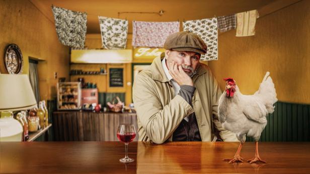 Mann mit Huhn am Tisch