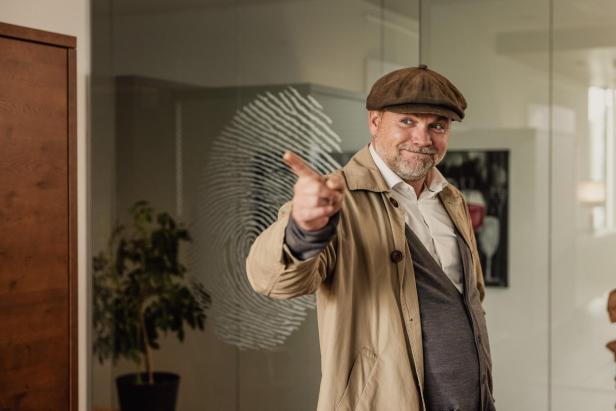 Ein Mann mit Mütze zeigt mit dem Finger auf die Kamera