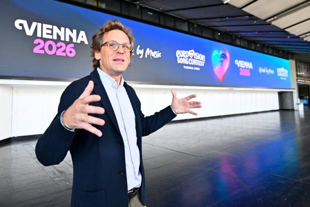 ++ THEMENBILD ++ EUROVISION SONG CONTEST (ESC) 2026: WIENER STADTHALLE / ZELENKA Ein Mann gestikuliert vor einer Wand mit der Aufschrift "Vienna 2026" und "Eurovision Song Contest Vienna 2026".