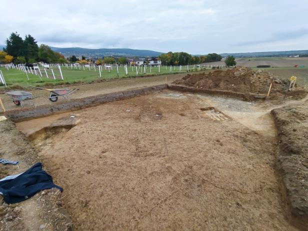 Eine Ausgrabungsstätte mit freigelegtem Erdreich und Erdhaufen ist zu sehen.