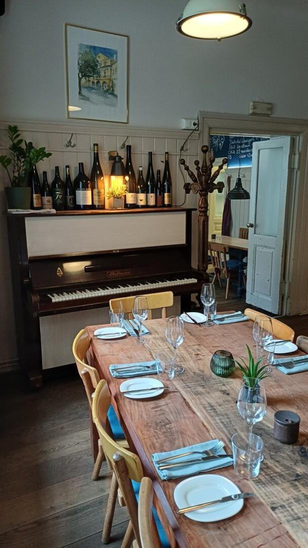 Die Gaststube des Vinzenz Pauli mit Klavier im Hintergrund, im Vordergrund der gedeckte Tisch, 