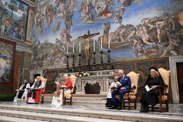 Britain's King Charles and Queen Camilla make their first state visit to the Holy See since Pope Leo XIV's election In einer Kirche sitzen König Charles und Camilla mit Geistlichen vor einem Altar mit Kruzifix und Wandmalereien.