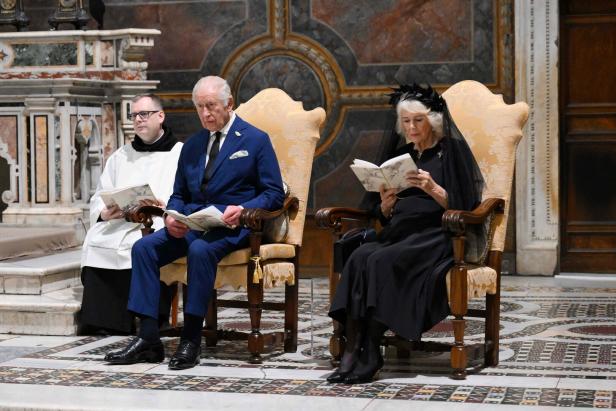 VATICAN-RELIGION-POPE-BRITAIN-ROYALS König Charles und Königin Camilla sitzen mit einem Geistlichen in einer Kirche und lesen.