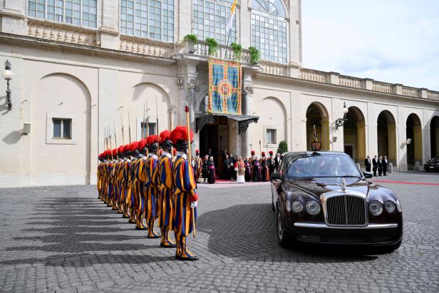 Britain's King Charles and Queen Camilla make their first state visit to the Holy See since Pope Leo XIV's election Eine Reihe von Schweizergardisten in bunten Uniformen steht Spalier vor einem Gebäude, während eine Limousine vorfährt.