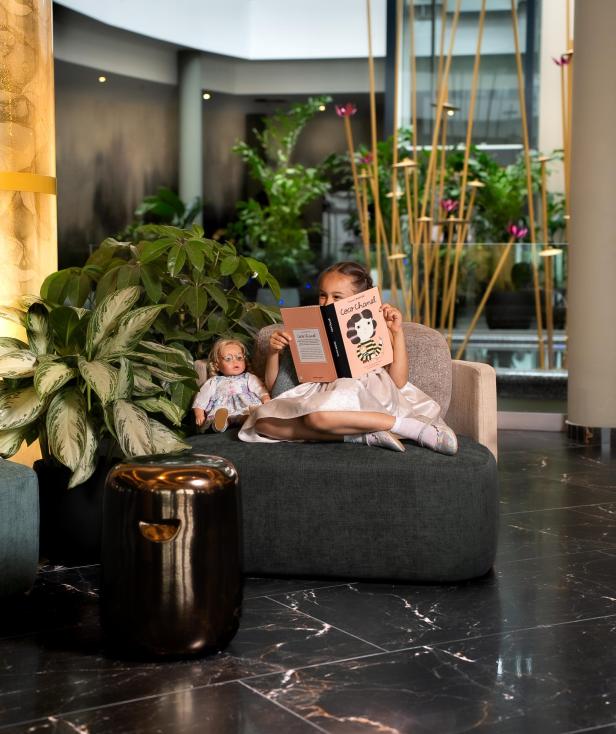 Kind in einer Hotellobby ist am Lesen