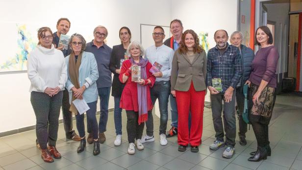 Eine Gruppe von Leuten steht in einer Galerie und präsentiert Bücher.