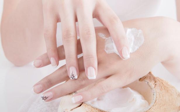 Eine Frau cremt mit einer Handcreme ihre Hände ein.