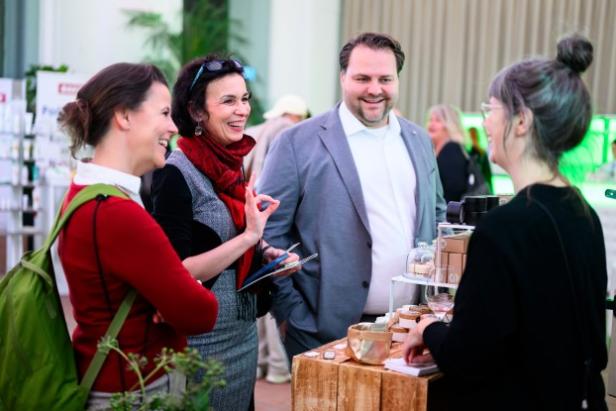 Menschen unterhalten sich bei einer Veranstaltung an einem Stand.