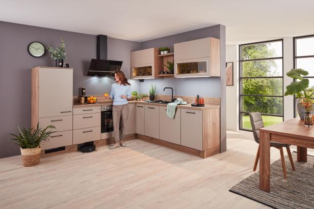 Moderne Küche mit Holzfronten, eingebautem Herd, Dunstabzugshaube und großen Fenstern, daneben Esstisch mit Stühlen und Zimmerpflanzen.