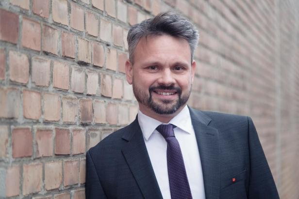 Ein Mann lehnt an einer Ziegelwand