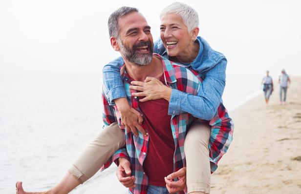 Ein älteres Paar am Strand, das liebevoll miteinander interagiert.