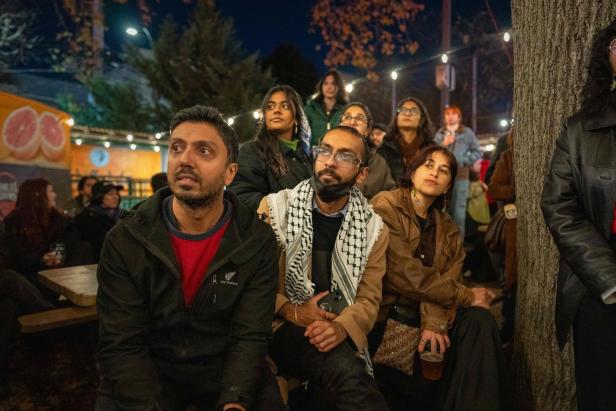 Eine Gruppe von Menschen sitzt abends draußen und schaut in die Ferne.