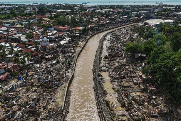 Ein Fluss fließt durch eine von Überschwemmungen und Zerstörung stark betroffene Siedlung mit vielen zerstörten Häusern.