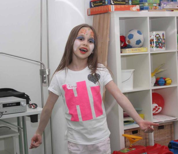 Ein Mädchen mit Gesichtsbemalung steht in einem Zimmer mit Spielsachen.