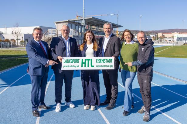 Sechs Personen stehen auf einer blauen Laufbahn und halten gemeinsam ein Schild mit der Aufschrift „Laufsport HTL Eisenstadt“.