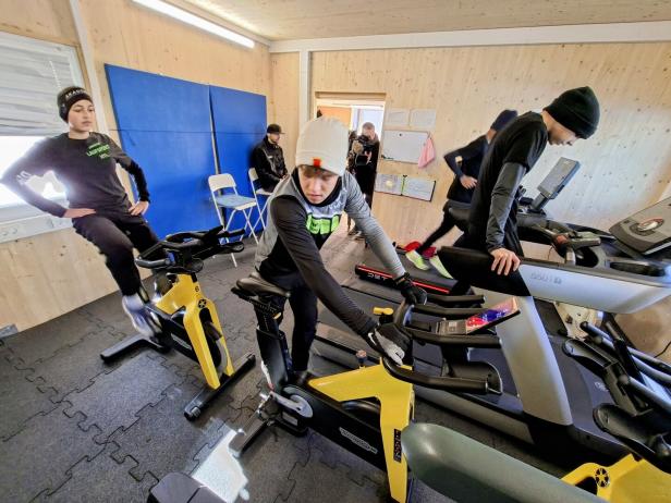 Mehrere Personen trainieren gemeinsam in einem Fitnessraum auf Fahrradergometern und Laufbändern.