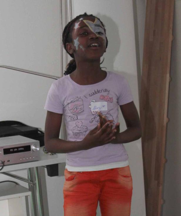 Ein Mädchen mit Gesichtsbemalung steht in einem Raum.