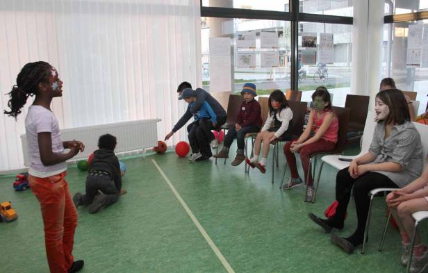 Kinder mit Gesichtsbemalung spielen in einem Raum mit Bällen.