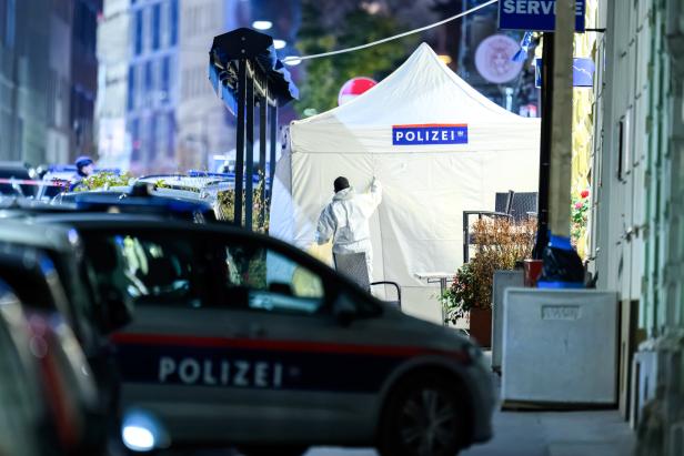 Ein Tatortzelt der Polizei steht auf der Straße, ein Beamter im Schutzanzug ist zu sehen.