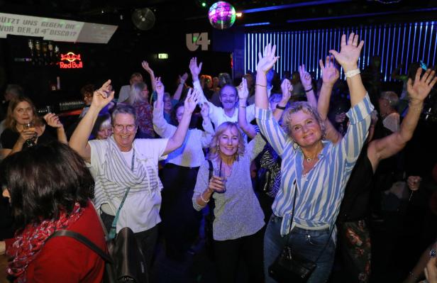 Senioren heben auf der Tanzfläche Hände in die Höhe