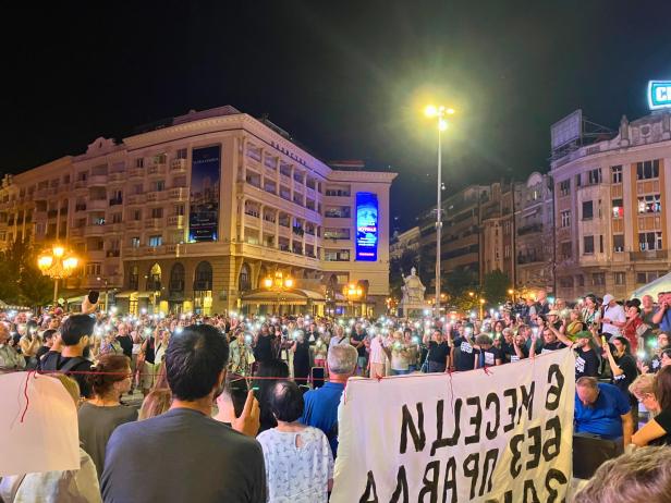 Schätzungsweise hundert Menschen versammeln sich bei einer Kundgebung am Abend und halten Handylichter in die Höhe