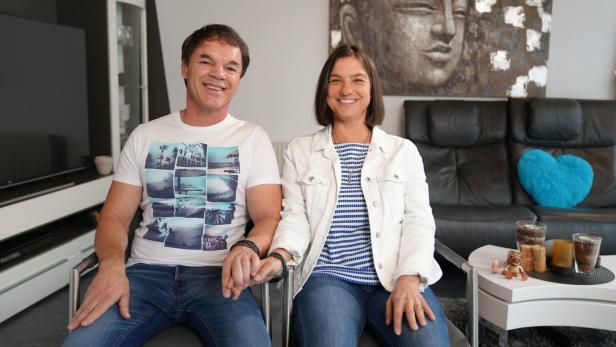 Hari und Isabella sitzen Hand in Hand nebeneinander.