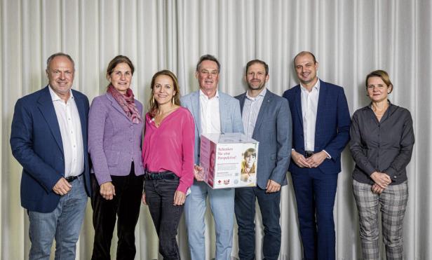 Mehrere Menschen stehen nebeneinander, Mann in der Mitte hält eine Box 