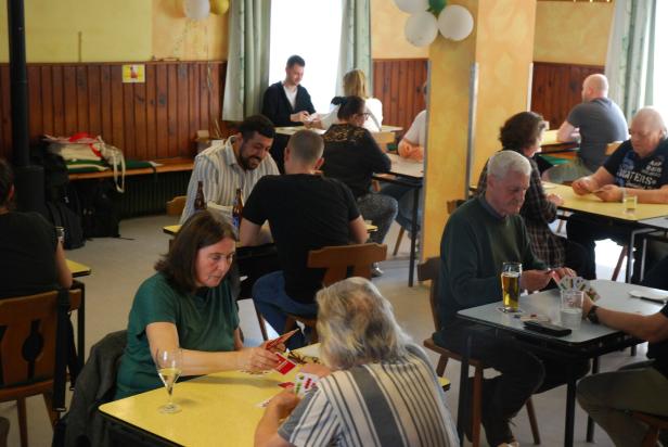 Mehrere Menschen sitzen an Tischen und spielen Karten