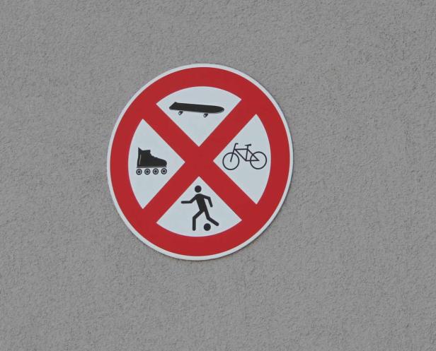Ein rundes Schild verbietet Skateboards, Inlineskates, Fahrräder und Fußballspielen.