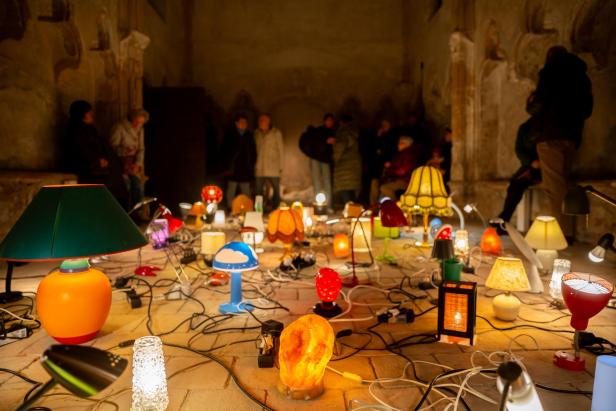 Mehrere Lampen in unterschiedlichen Formen und Farben stehen am Boden Ursulakappelle in Krems.