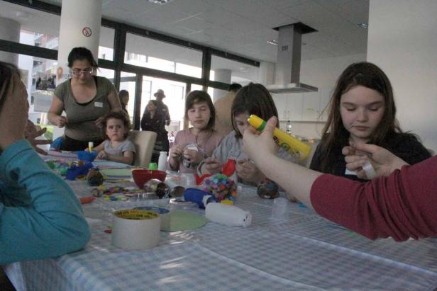 Kinder basteln gemeinsam an einem Tisch mit verschiedenen Materialien.