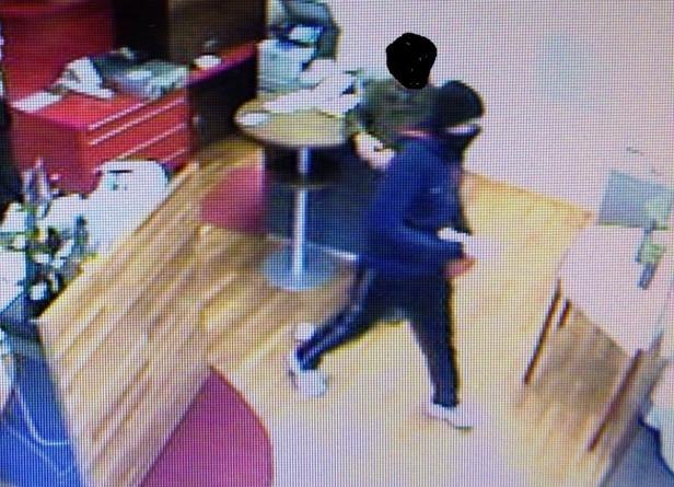 Eine Person in dunkler Kleidung geht in einem Innenraum umher.