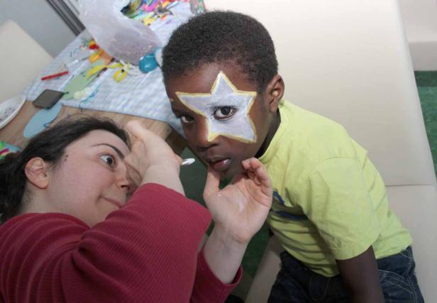 Eine Frau bemalt das Gesicht eines Jungen mit einem Stern.