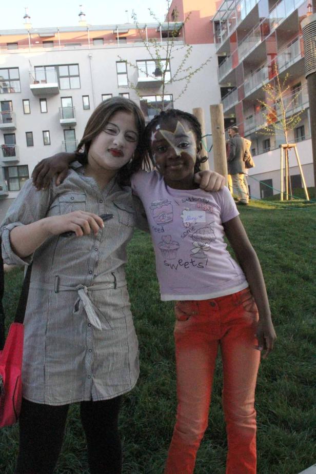 Zwei Mädchen mit Gesichtsbemalung umarmen sich im Freien.