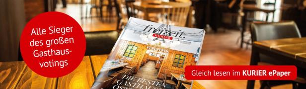 Das Magazin „freizeit.KURIER“ mit dem Titelthema „Die besten Gasthäuser Österreichs“ liegt auf einem Holztisch in einem gemütlichen Wirtshaus.
