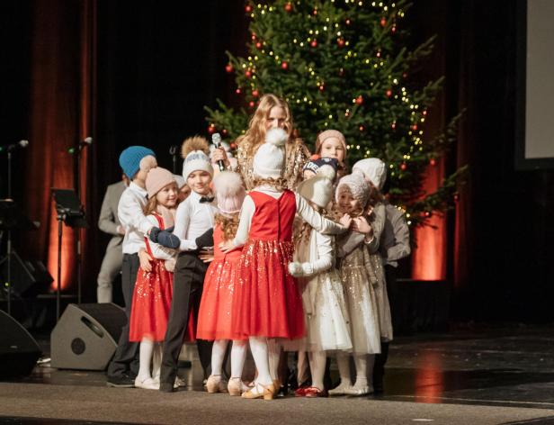 Eine Gruppe Kinder in weihnachtlichen Kostümen steht auf einer Bühne.