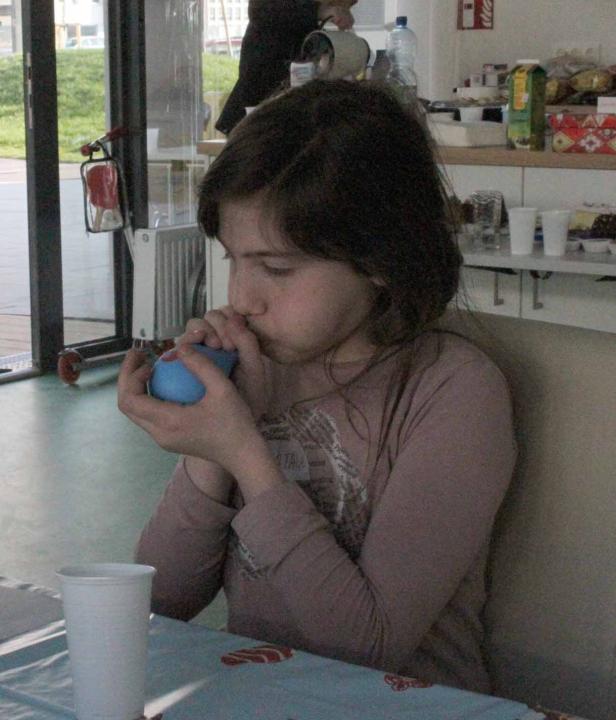 Ein Mädchen pustet einen blauen Ballon auf.