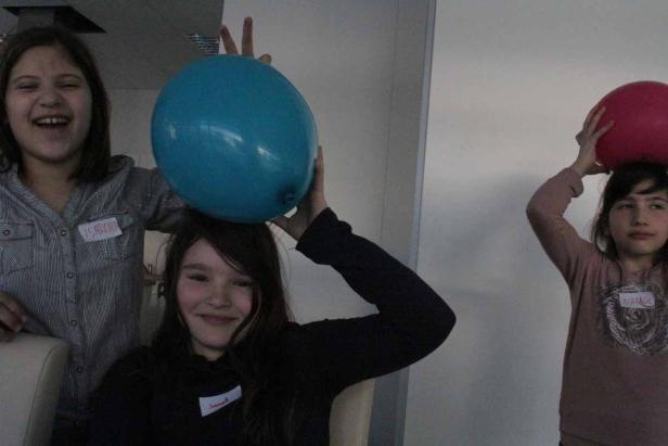 Drei Mädchen, Isabelle, Hannah und Natalie, balancieren Ballons auf ihren Köpfen.