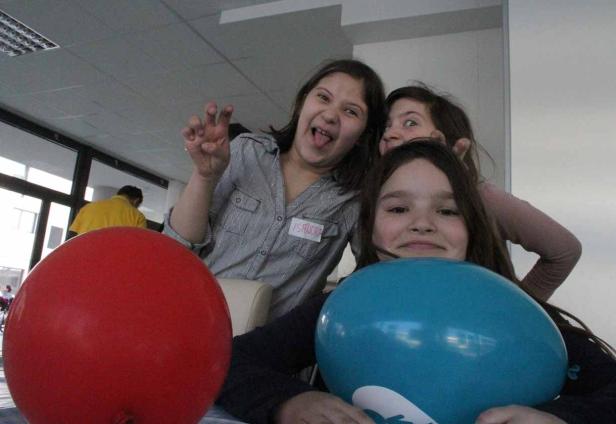 Drei Mädchen posieren mit einem roten und einem blauen Ballon für ein Foto.