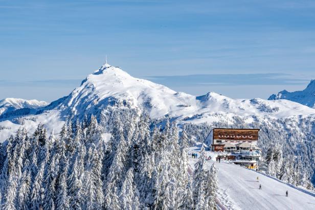 Blicks auf den verschneiten Berg Kitzbüheler Horn, davor steht ein altes Gebäude.