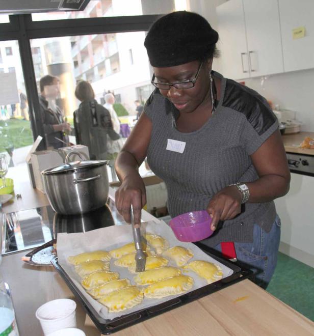 Eine Frau bestreicht Teigtaschen auf einem Backblech mit einer Flüssigkeit.