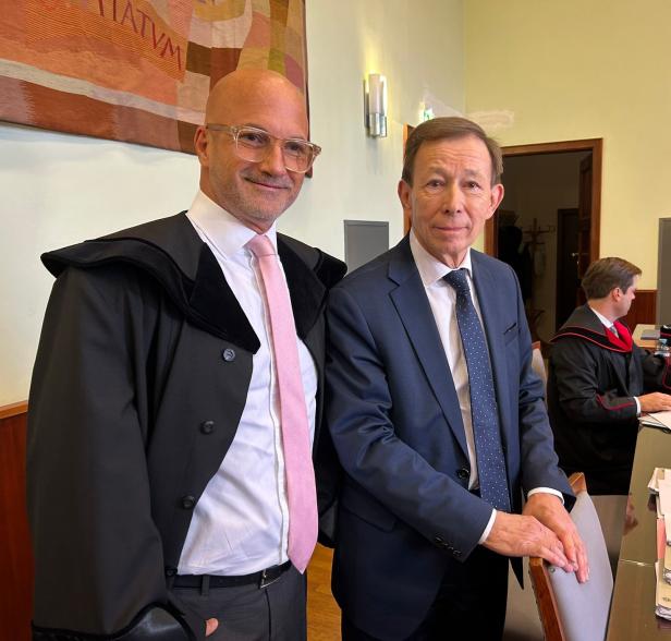 Zwei Rechtsanwälte stehen im Gerichtssaal